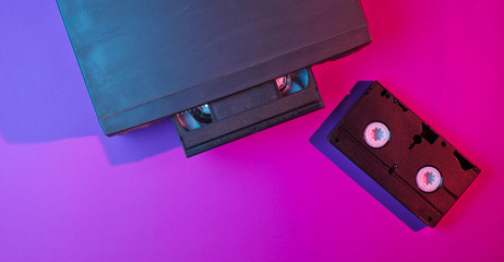 Retro wave, minimalism 80s concept. Video player with vhs cassette, neon light. Night life. Top view