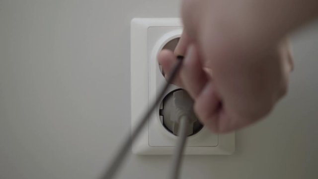 Female hand puts a power plugs in the wall socket. 4K