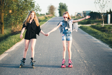 Teenage smiling happy girls having fun rollerskating together