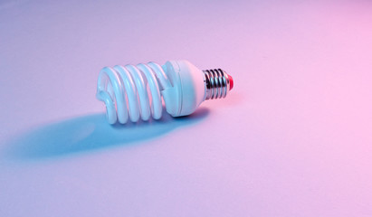 Spiral eco light bulb on neon light background. Minimalism concept