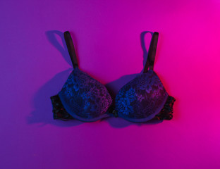 Erotic concept. Women's sexy bra, neon pink light. Top view