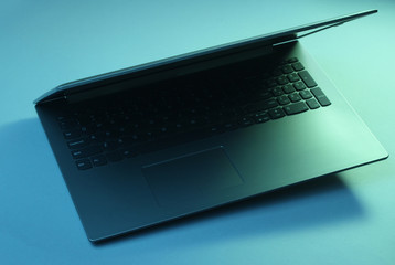 Modern laptop with vibrant gradient green blue holographic color lights. Minimal office surrealism...