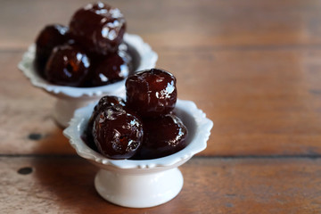 Sweet Jujube or Chinese red date in syrup in white Thai style cup on wood table and space for write wording, Clever idea for fresh fruit preservation, popular sweet, unhealthy food cause of disease