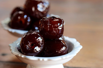 Sweet Jujube or Chinese red date in syrup in white Thai style cup on wood table and space for write wording, Clever idea for fresh fruit preservation, popular sweet, unhealthy food cause of disease