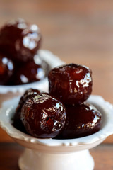 Sweet Jujube or Chinese red date in syrup in white Thai style cup on wood table and space for write wording, Clever idea for fresh fruit preservation, popular sweet, unhealthy food cause of disease