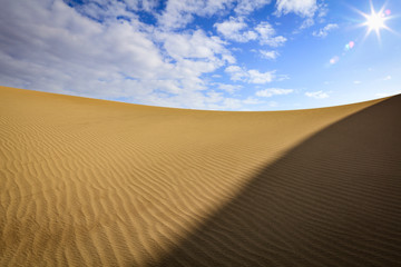 Summer background of sand on beach and blue sky with sun light. Free space for your decoration. 