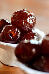 Sweet Jujube or Chinese red date in syrup in white Thai style cup on wood table and space for write wording, Clever idea for fresh fruit preservation, popular sweet, unhealthy food cause of disease