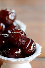 Sweet Jujube or Chinese red date in syrup in white Thai style cup on wood table and space for write wording, Clever idea for fresh fruit preservation, popular sweet, unhealthy food cause of disease