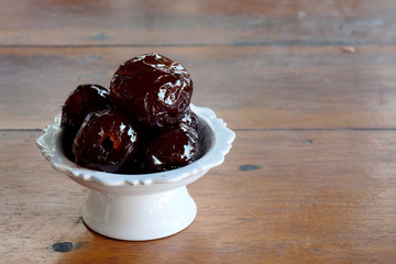 Sweet Jujube or Chinese red date in syrup in white Thai style cup on wood table and space for write wording, Clever idea for fresh fruit preservation, popular sweet, unhealthy food cause of disease