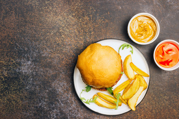 An american burger with fried potatoes on the white plate.