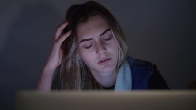 Serious, tired girl works with laptop at night. 4K