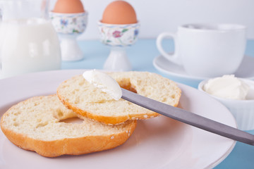 Fresh healthy bagel on a white napkin with cup of coffee, cream cheese and eggs for breakfast.