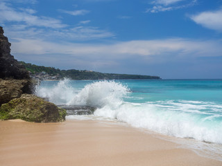 Fototapeta premium Turquoise waves crash against stones with splashes. Bali.
