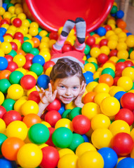 Fototapeta na wymiar Happy little girl playing and having fun at kindergarten with colorful balls in play center