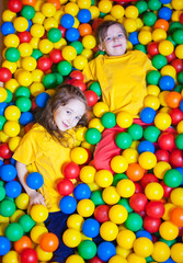 Fototapeta na wymiar Two Happy little girls playing and having fun at kindergarten with colorful balls in play center