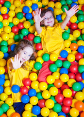 Two Happy little girls playing and having fun at kindergarten with colorful balls in play center
