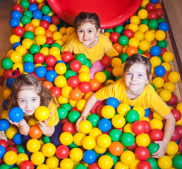 Fototapeta na wymiar Three Happy little girls playing and having fun at kindergarten with colorful balls in play center