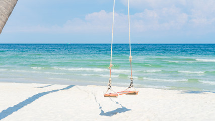 Swing on the beautiful beach with white sand and crystal clear blue water background for tourism concept