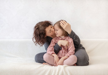 Young woman with her daughter are resting on the sofa.
