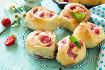 Fresh Homemade Rolls Buns with strawberry with Cream Cheese in glaze for Breakfast on kitchen table. Copy space.