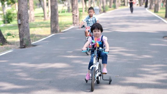 Asian cute child girl are enjoying a bike ride in the park on the street. Asian cute child girl are enjoying a bike ride in the park on the street. Slow motion..