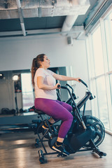 Fototapeta na wymiar Fat woman intensely exercising on stationary bike