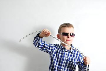 Boy with sunglasses and checked shirt holding a rope in his hands