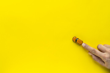 Woman hand with Little Yellow toy car on a yellow background. Free space for text