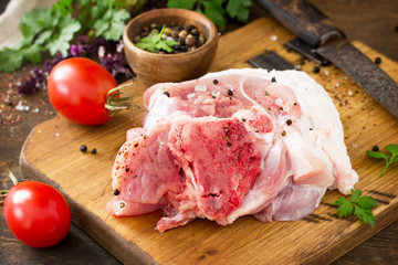 Fresh raw meat. Raw pork meat steak with olive oil, tomatoes and herbs on wooden table.