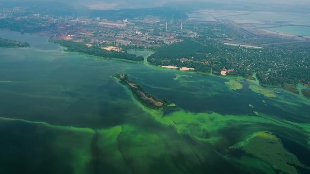 aerial of wide river polluted with green algae near industry zone