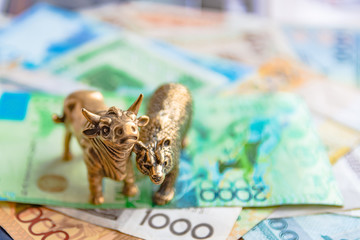 Bronze figures of a bull and a bear on the background of paper money and metal coins. Blur...