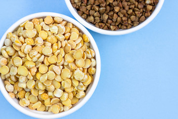 buckwheat and peas in plates, top view, on a blue background, copy space