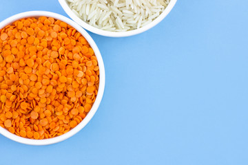rice and lentils in plates, top view, on blue background, copy space