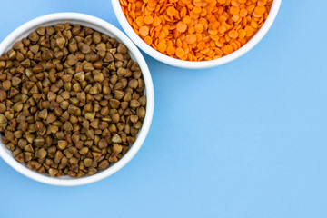 buckwheat and lentils in plates, top view, on blue background, copy space