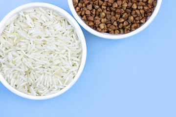 rice and buckwheat in plates, top view, on a blue background, copy space