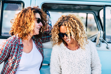 Happy people outdoor - couple of curly cute middle age adult women friends enjoy together the trip...