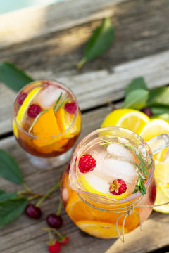 Homemade refreshing drink. Wine sangria or punch with fruits in glasses, cocktails with fresh fruits, berries and rosemary on a wooden rustic table.