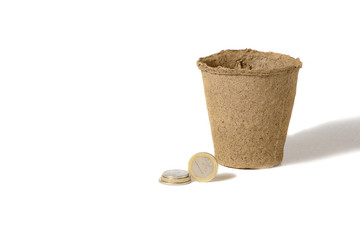 Coin and a peat pot for seedlings lying together, in a rural agricultural production company isolated over white.