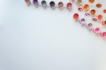 Paints flatlay on white background. Orange, yellow, lilac, broun. Top view.