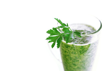 Green fruit and vegetable smoothie with a sprig of parsley in a transparent glass mug on a white background. healthy diet. food high in vitamins