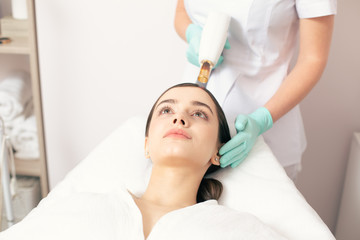 Face of young woman and medical worker using laser tool