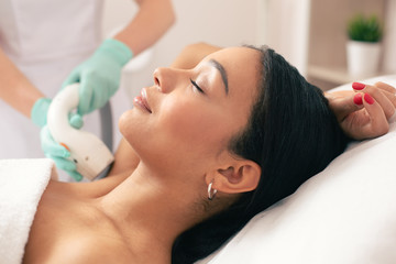Obraz na płótnie Canvas Side view of calm woman at the laser hair removal procedure