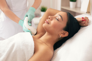Young woman relaxing at the laser hair removal procedure - obrazy, fototapety, plakaty
