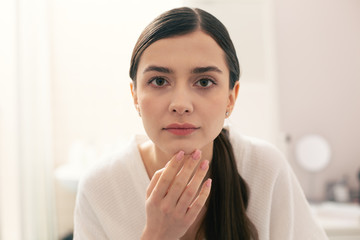 Long haired woman touching her chin and looking interested