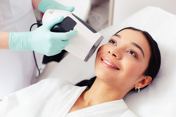 Cheerful woman having her skin analyzed with special device