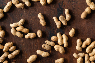 Top view of raw peanuts in shell, texture on wooden background.
