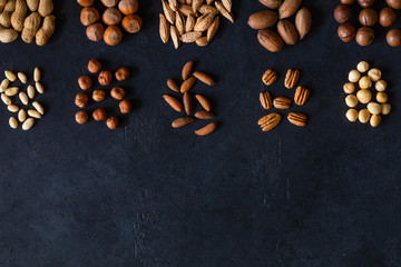 Various nuts on black stone table. Top view frame with copy space