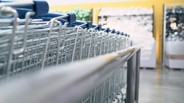 Young Asian Woman Rides Shopping Cart Choosing New Furniture In Warehouse, Teenager Female Feeling Happy In Front Of Shelves In Department Store. Close-up Shot Women Shopping New Furniture Concept.