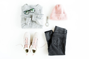 Women fashion clothes and accessories. Feminine youth collage on white background top view. Flat lay female style look with warm sweater, jeans, hat, sneakers, glasses. Top view.