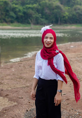  Women muslim, women islamic,wearing a red fabric head covering adorn with white fabric flowers wear shirt white wear black pants standing poses on the beach before to ramadan month.